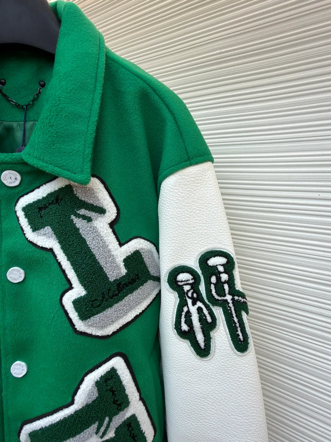 LOUIS VUITTON Loose long-sleeved baseball jersey with monogram pattern ●Original version: Purchased and developed for 29999 ●Item number: 1682254-C10 ●Fabric: cotton fabric ●Technology: embroidery production ●Color: green ●Version: fitted version ●Weight: about 1145 grams ●Size: 46-48-50-52 ●Description: The main body of this Louis Vuitton baseball jacket is made of high-count wool blended fabric. It has been processed by raising and carding processes. The fabric has a full velvety feel and is crisp and stylish. The green base color is made of worsted dyeing process. The color is pure and not easy to fade. The sleeves are spliced ​​with custom pebbled artificial leather, which has been embossed and softened. The texture is natural, flexible to the touch, and is scratch-resistant and wear-resistant. The letters and patterns decorated on the body are made of terry embroidery + appliqué embroidery composite technology. The terry embroidery coils are fluffy and three-dimensional, and the edges of the appliqué embroidery are overlocked to ensure accurate pattern splicing. The handwritten text is made using flat embroidery technology, with fine stitches and clear fonts. The placket is made of custom-made mother-of-pearl buttons, which are hand-polished and polished to have a warm luster; the ribbed neckline and hem are made of spandex blended material, which has good resilience and is not easy to loosen. The overall design uses three-dimensional tailoring and hand-sewing techniques to integrate a variety of materials and embroidery techniques to fully demonstrate the essence of haute couture garments. The overall wiring is straight and delicate, the fabric is comfortable and soft, and the color is consistent without color difference. It can be matched with the same style to create a fashionable look and control various occasions. Customized accessories, complete with three standards, same style for men and women!